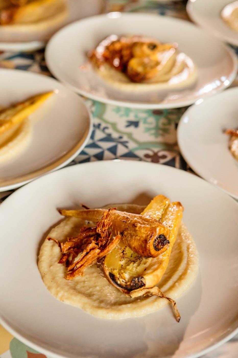 A chef-plated course on a Mediterranean-tiled table
