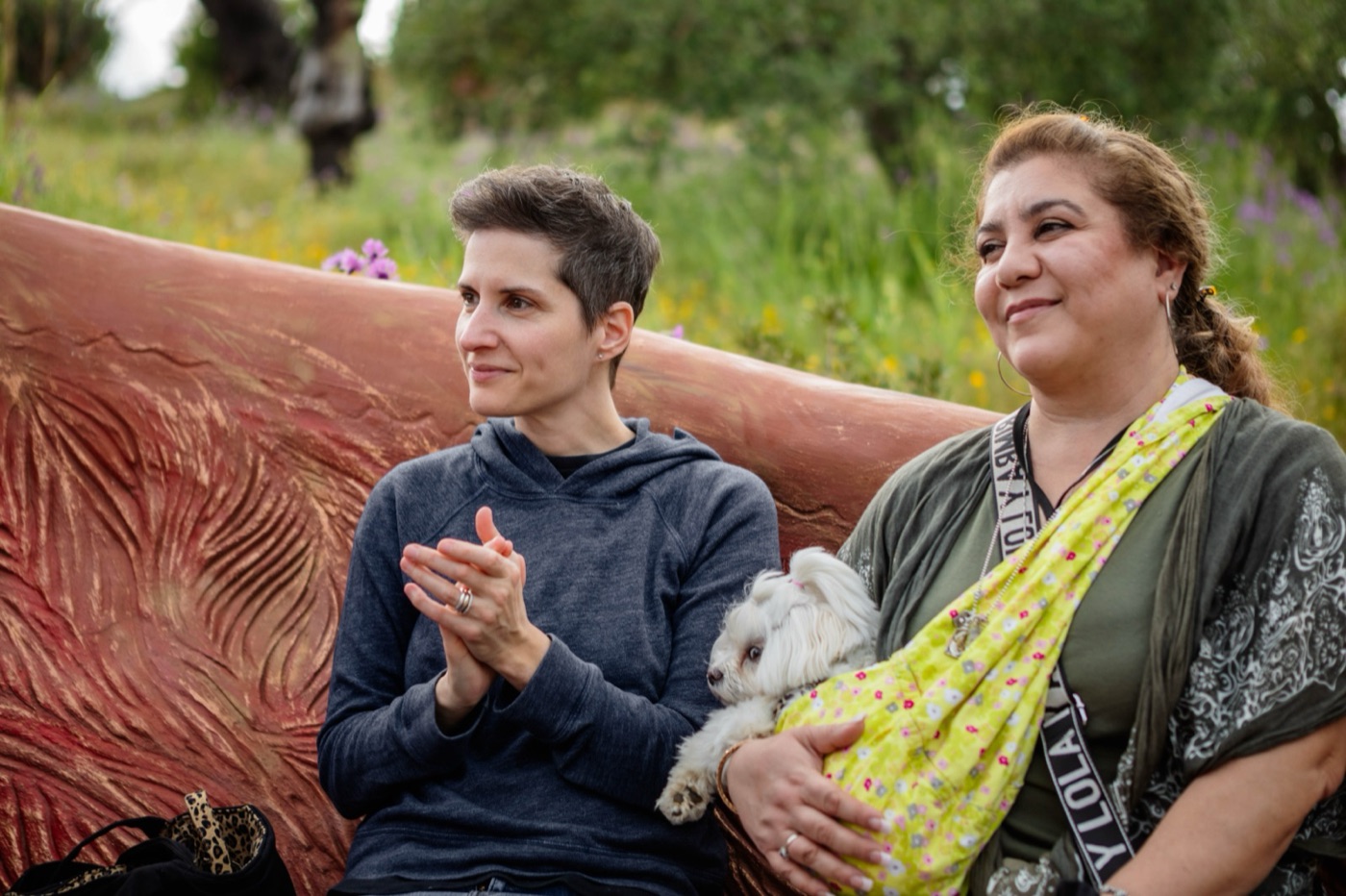 Two guests resting on the sculpted bench with a dog